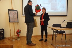 Zofia Kostka - Bieńkowska otrzymuje kwiaty i upominek od prowadzącego spotkanie.